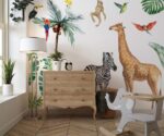 Safari animals wall decals for nursery featuring a giraffe, zebra, and monkey with tropical birds and palm trees above a white crib.